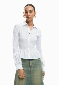 Valge ja helesinise triibuline särk krinkitud ülakehaga, nööbitava esiosa, terava kraega ning laia, plisseeritud varrukatega.