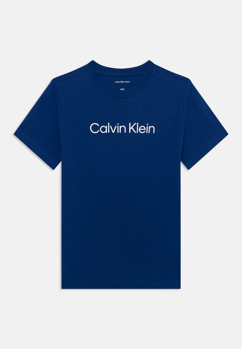 Mėlynas medvilninis marškinėliai su apvalia iškirpte, trumpomis rankovėmis, ant krūtinės užrašyta balta spalva „Calvin Klein“ logotipas.