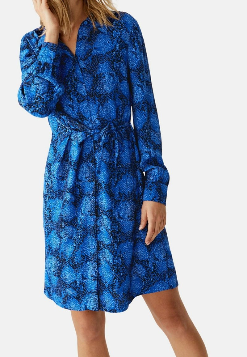 Abito camicia con stampa serpente blu, maniche lunghe, chiusura con bottoni e cintura da annodare in vita; realizzato in tessuto liscio con un motivo testurizzato.