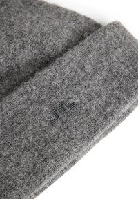 Harmaa neulottu pipo, joka on valmistettu pehmeästä, teksturoituneesta villasta ja jossa on pieni musta logopatentti edessä. Yksinkertainen muotoilu, jossa on käännettävä cuff.