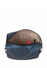 Blauwe ritsen tas met een gladde buitenkant, beige binnenvoering, meerdere compartimenten en een kleine ritszak aan de binnenkant. Beschikt over branding.