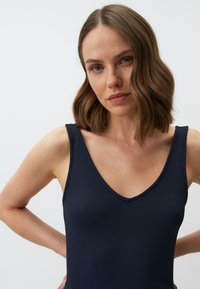 Costume da bagno intero a righe navy con scollatura a V e spalline larghe, caratterizzato da una texture liscia e una silhouette aderente.