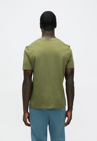 Olivgrünes T-Shirt mit kurzen Ärmeln, rundem Ausschnitt und glatter Struktur. Einfaches Design ohne sichtbare Muster oder Akzente.