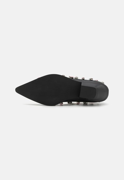 Pointed-toe black shoe with a smooth sole and decorative metal studs in various colors along the side. Flat, stable heel design.