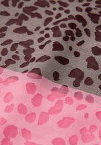 Tissu brun et rose avec des motifs abstraits d'animaux superposés, mettant en valeur la texture et de légers plis.