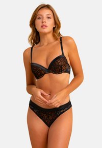 Ensemble de lingerie en dentelle noire comprenant un soutien-gorge structuré avec des motifs floraux orange et un string assorti avec une taille en satin. Les accents incluent des bretelles ajustables.