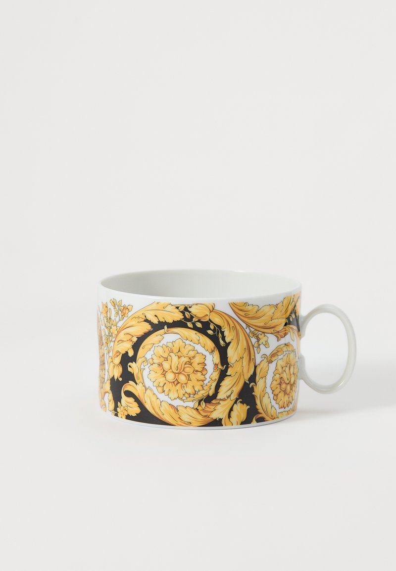 Κεραμική κούπα με καμπυλωτό σχήμα, που διαθέτει μαύρη βάση και περίπλοκα χρυσά λουλουδάτα σχέδια. Διαθέτει απλή λευκή λαβή.