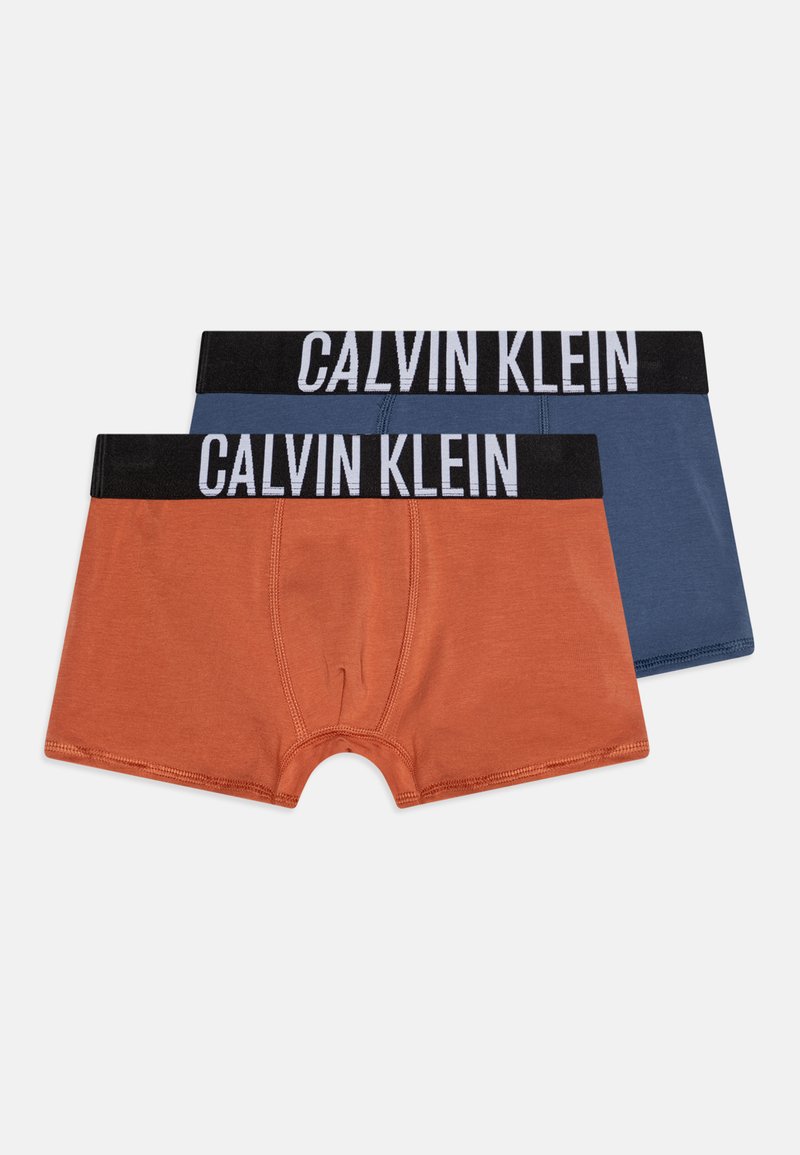 Due paia di boxer da uomo. Uno è color arancio ruggine e l'altro è blu navy. Entrambi hanno una cintura nera con la scritta "CALVIN KLEIN" in lettere bianche.