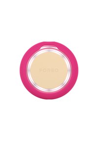 Foreo compact with a pink silicone outer casing and a clear inner rim. Features a smooth beige surface with embossed lettering "FOREO."