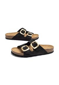 Chanclas negras de ante con dos hebillas doradas, suela de corcho y suela exterior de goma negra texturizada. Presentan un diseño abierto.
