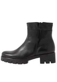 Bottine en cuir noir avec un bout rond, une semelle épaisse et striée, et une fermeture discrète par zip à l'arrière. Texture lisse.