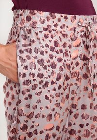 Lekkie, szare dresy w panterkę z różowymi akcentami. Posiadają elastyczny pas, sznurek oraz boczne kieszenie. Gładka tekstura.