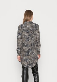 Camicia a maniche lunghe a motivi in blu scuro e crema, con tessuto strutturato e punti sparsi e colletto a camicia.