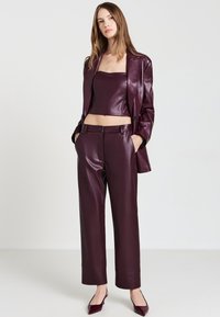 Bordeauxfarbener Lederblazer, Crop-Top und weit geschnittene Hose; elegantes Design mit glatter Textur und minimalem Hardware. Passende spitze Absätze.