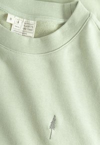 Felpa verde chiaro con scollatura rotonda. Presenta un design di albero ricamato in grigio sulla parte inferiore sinistra. Texture morbida, design casual.