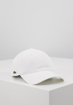 Witte katoenen honkbalpet met een gebogen klep en een geborduurd groen Lacoste-logo aan de linkerkant. Voorzien van een verstelbare strap aan de achterkant.