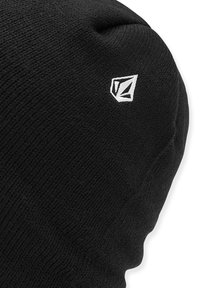 Sort strik beanie med en tekstureret overflade. Har et hvidt logo på siden. Blødt materiale med et afslappet design.