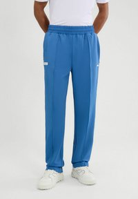 Niebieskie spodenki sportowe o teksturowanym wykończeniu, z elastycznym pasem i kieszeniami bocznymi. W zestawie z białymi trampkami.