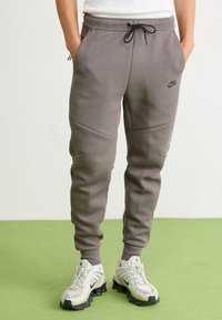 Szare spodnie dresowe Nike wykonane z miękkiego materiału, z elastycznym paskiem ze sznurkiem, bocznymi kieszeniami i eleganckim, zwężanym krojem.