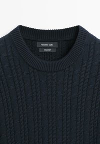 Tmavě modrý bavlněný svetr s copánkovým vzorem, s žebrovaným kulatým výstřihem a štítkem Massimo Dutti přišitým na vnitřní straně límce.