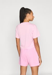 Rosa Baumwoll-T-Shirt mit kurzen Ärmeln und lockerem Schnitt, kombiniert mit rosa Baumwoll-Shorts, die eine glatte Textur und ein einfaches Design aufweisen.