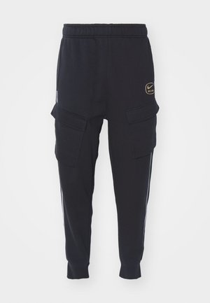 Juodos sportinės kelnės su elastinga juosta, šoninėmis cargo kišenėmis, baltais šonų dryžiais ir auksiniu Nike Air logotipu priekyje. Minkšta tekstūra, aptemptas siluetas.