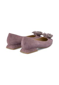 Ballerine in suede viola con un tacco basso e angolare e decorazioni floreali sui punte. Texture liscia e linee di design pulite.