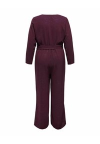 Bordeaux jumpsuit met lange mouwen en een ceintuur om de taille. Textuurstof met subtiele glinsterende details. Wijd uitlopende pijpen.
