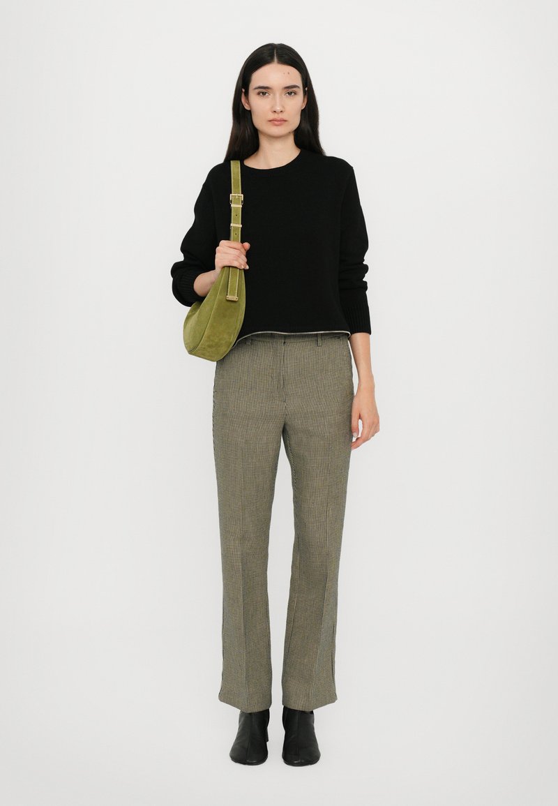 Black knitted sweater, green suede handbag, checkered trousers with a straight fit, black ankle boots, minimal design, neutral background.