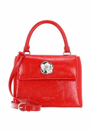 Sac à main en cuir verni rouge avec poignée supérieure, bandoulière détachable, fermoir floral argenté et logo Ted Baker London sur le devant.