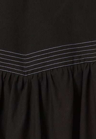 Tissu noir avec un bord inférieur froncé. Contient des lignes de couture horizontales blanches en haut, ajoutant texture et détail.
