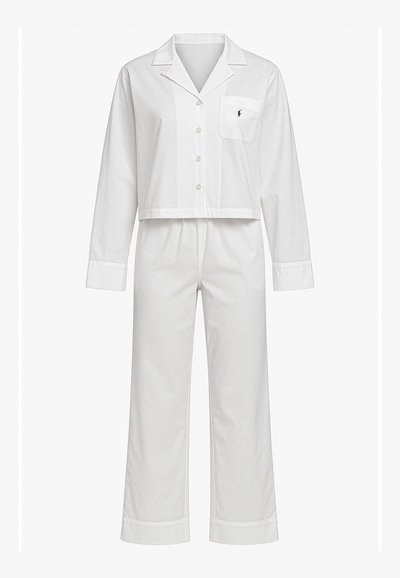 Set di pigiama in cotone bianco con maniche lunghe, camicia con bottoni e taschino sul petto, e pantaloni a gamba dritta con risvolti.