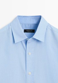 Světle modrá pruhovaná košile, bavlněný materiál, klasický límeček, s knoflíkovou légou s bílými knoflíky a s etiketou značky uvnitř límečku.