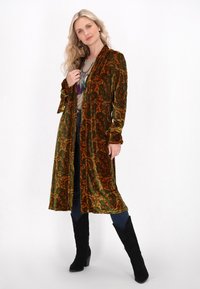 Pitkä, avointa etuosaa oleva kimono, joka on valmistettu pehmeästä, kuvioidusta sametista, vihreänä oransseilla paisley-kuvioilla. Siinä on pitkät hihat ja rento malli.