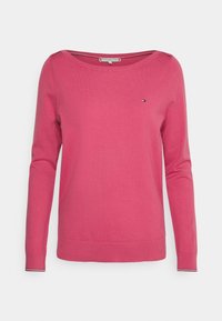 Maglione rosa a maglia con scollatura ampia e maniche lunghe. Presenta un piccolo logo sul petto e dettagli a righe nei polsini.