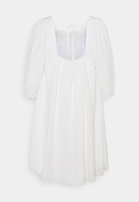 Robe blanche ample avec manches bouffantes, encolure carrée et détail noué sur la poitrine, fabriquée en tissu léger.