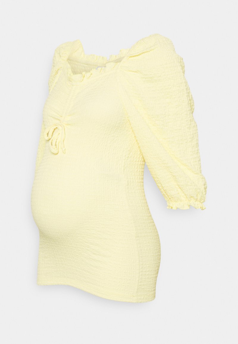 Top amarelo, texturizado, com mangas bufantes, detalhe de cordão ajustável no decote e bainha curva, projetado para uma silhueta ajustada.