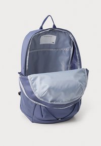 Blue backpack with a large flap, mesh side pocket, and a lighter blue interior. Includes a label for personal identification inside.