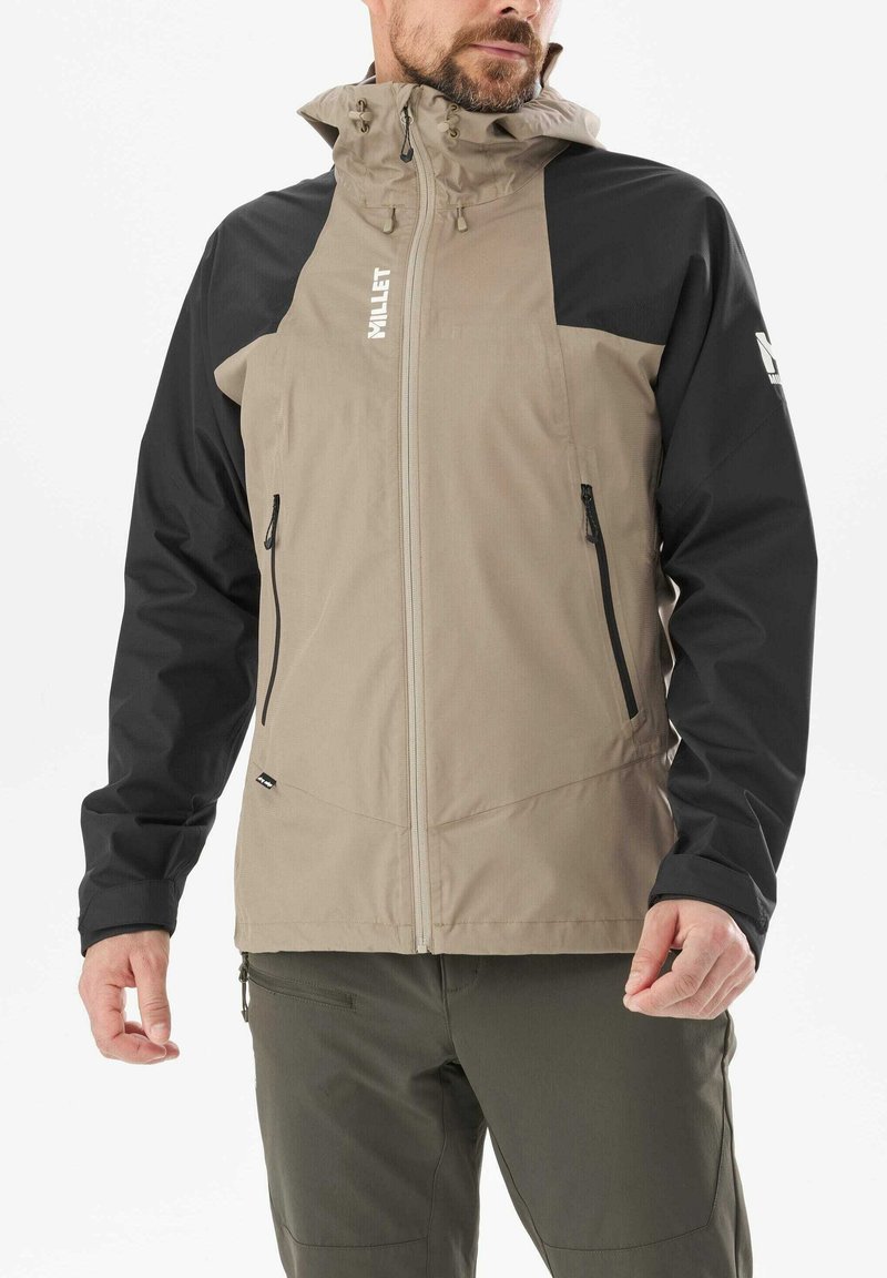 Beige- und schwarze, wasserdichte Jacke mit durchgehendem Reißverschluss, verstellbarer Kapuze und zwei Seitentaschen. Mit einem Logo auf der Brust.