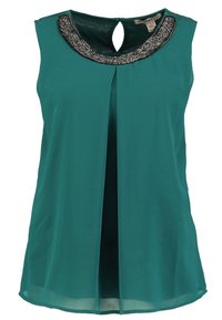 Hihaton teal-värinen pusero avonaisella selkäosalla, koristeltu helminauhalla kaula-aukossa. Kevyt kangas, väljä istuvuus ja laskos edessä.