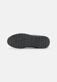 Semelle de chaussure en caoutchouc noir avec un profilé à motifs pour une meilleure traction. Présente un bord lisse et une légère courbe au niveau du talon.
