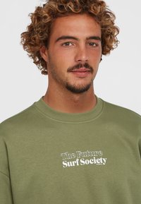 Oliven grøn sweatshirt med rund hals, prydet med hvid tekst "The Future Surf Society" trykt på forsiden. Blødt bomuldsblanding stof.