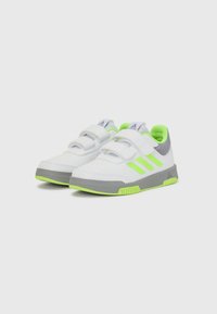 Zapatillas deportivas blancas con detalles en gris y verde lima. Cuentan con correas ajustables de Velcro y suelas texturizadas para un mejor agarre.