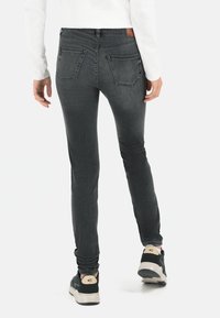 Jeans negros ajustados con una textura suave y un desvanecimiento mínimo. Presenta dos bolsillos traseros, una etiqueta de marca en la cintura y un corte slim.
