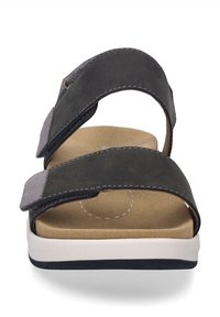 Czarne skórzane sandały z dwoma regulowanymi paskami, wyściełaną brązową wkładką i białą gumową podeszwą z czarnym akcentem.