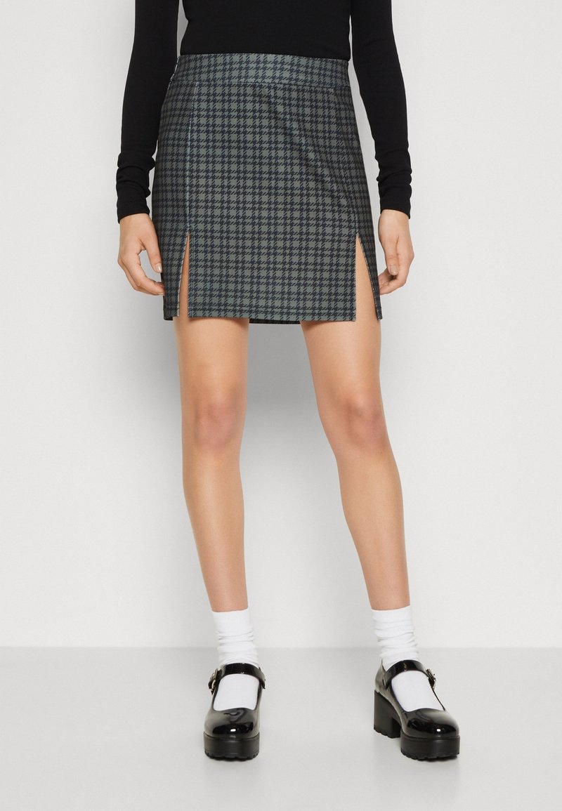 Svart och grått houndstooth-minikjol med framklippningar, med en mjuk textur. Buren med vita strumpor och svarta plattformsskor.