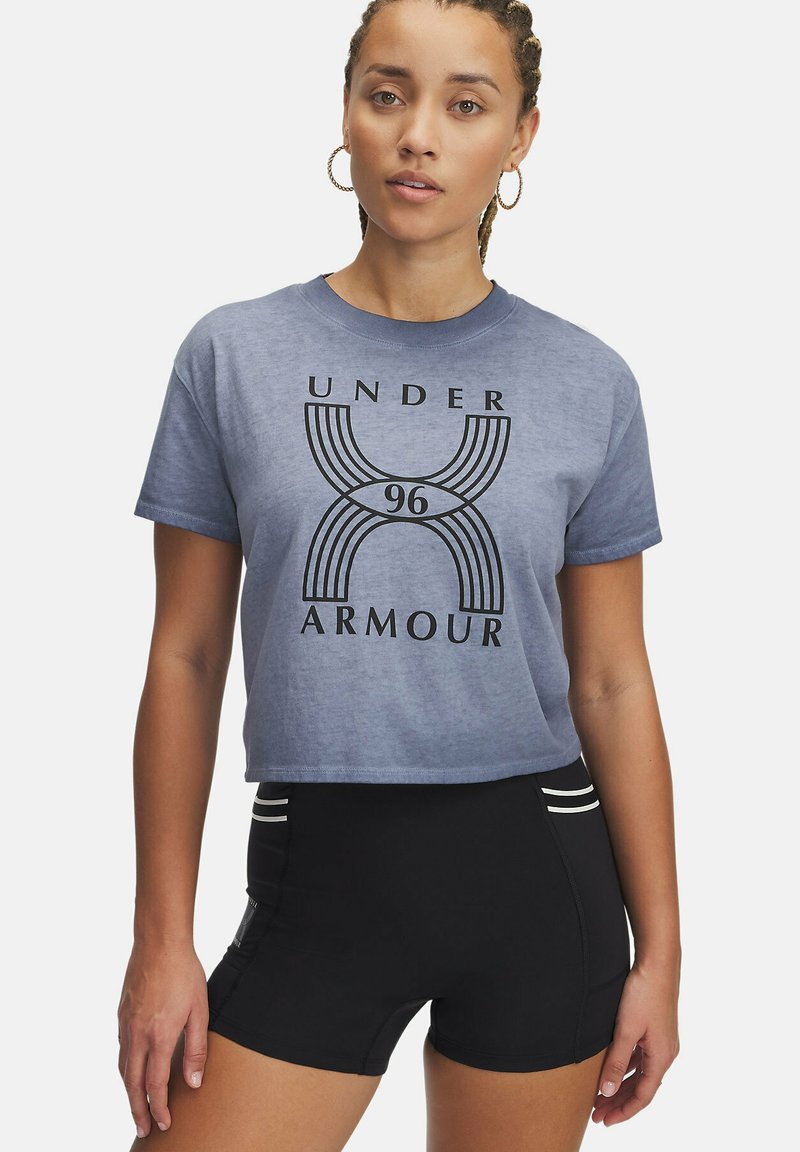 Kort gesneden blauwe t-shirt met een zwart grafisch ontwerp van "UNDER ARMOUR 96", gecombineerd met zwarte sportshorts met witte accenten.