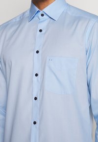 Lichtblauw overhemd met knopen, voorzien van een borstzak, zwarte knopen en een gladde textuur. Heeft een gespreide kraag en een getailleerd ontwerp.