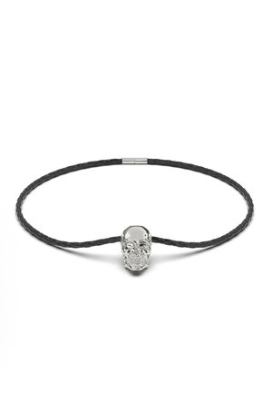 Black braided cord necklace featuring a silver skull pendant with detailed facial features and shine. Distinctive and modern design.