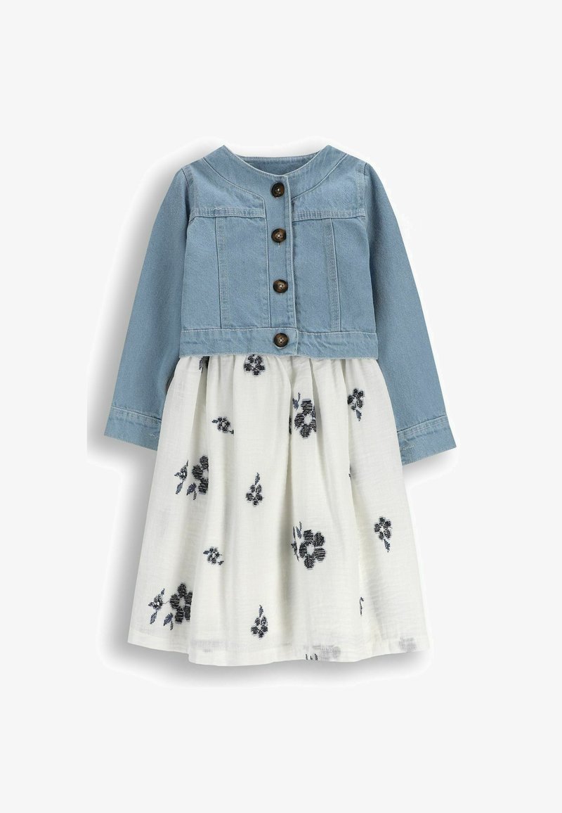 Dżinsowa kurtka z guzikami z przodu, dopasowana do białej sukienki z czarnym haftem kwiatowym. Komplet ma długie rękawy i rozkloszowaną spódnicę.